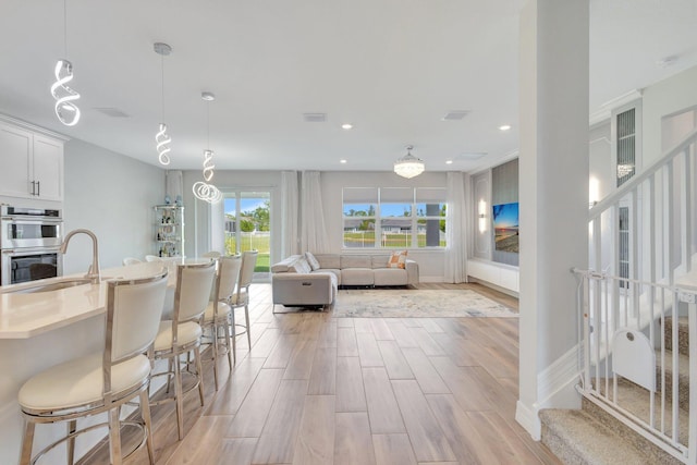 5322 Yellow Water Lily Ct, Lake Worth, FL 33467 - kitchen with a breakfast bar, a sink, white cabinets, light wood finished floors, and stainless steel double oven