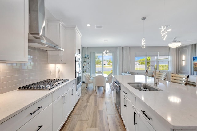 5322 Yellow Water Lily Ct, Lake Worth, FL 33467 - kitchen with wall chimney range hood, stainless steel appliances, a sink, decorative backsplash, and a kitchen island with sink
