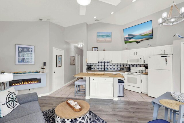 9927 Perfect Dr Unit 108, Port Saint Lucie, FL 34986 - living room featuring light wood-style floors, a glass covered fireplace, ceiling fan, and high vaulted ceiling