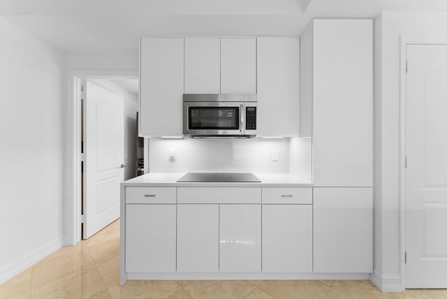 550 SE Mizner Blvd Unit B206, Boca Raton, FL 33432 - kitchen with stainless steel microwave, black electric stovetop, white cabinets, and light countertops