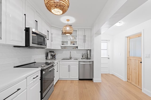 1517 NW 12th Ave, Fort Lauderdale, FL 33311 - kitchen featuring stainless steel appliances, a sink, light wood-style flooring, decorative backsplash, and white cabinets