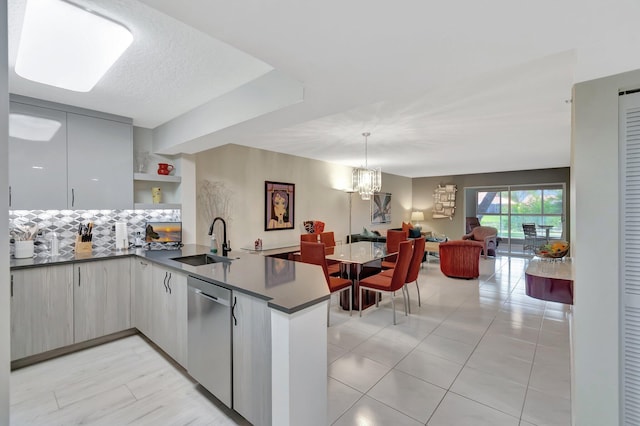5876 Regal Glen Dr Unit 103, Boynton Beach, FL 33437 - kitchen with dishwasher, a sink, a peninsula, dark countertops, and backsplash