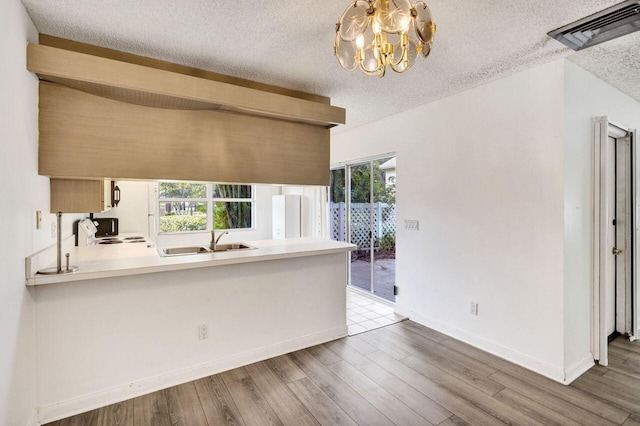 8155 Chelsea Ct Unit 55A, West Palm Beach, FL 33406 - kitchen featuring a sink, a chandelier, a textured ceiling, baseboards, and wood finished floors