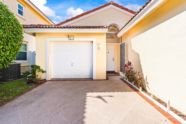 5618 Kingsmill Ct, Greenacres, FL 33463 - entrance to property with stucco siding, central AC unit, a garage, concrete driveway, and a tiled roof