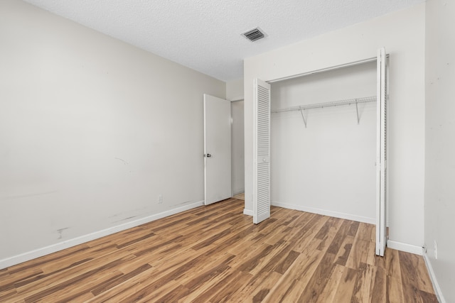 5618 Kingsmill Ct, Greenacres, FL 33463 - unfurnished bedroom featuring wood finished floors, a closet, baseboards, and a textured ceiling