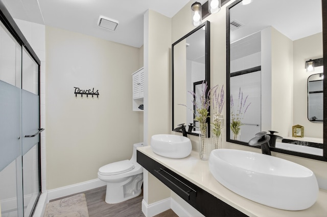 2703 Maplewood Dr, Greenacres, FL 33415 - full bath featuring wood finished floors, baseboards, a stall shower, double vanity, and toilet