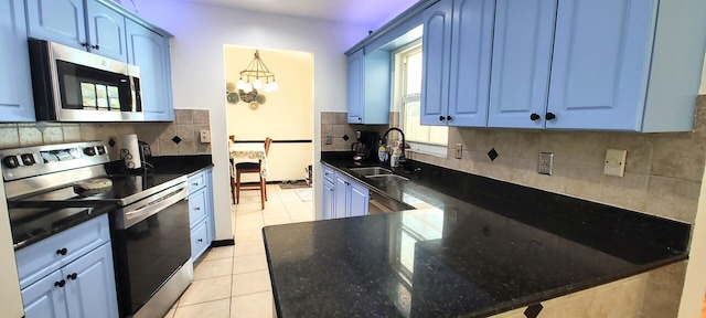 1514 SE Manth Ln, Port Saint Lucie, FL 34983 - kitchen featuring stainless steel appliances, a sink, blue cabinets, light tile patterned flooring, and decorative backsplash