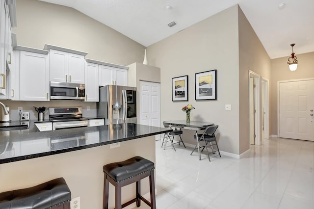 9308 Swansea Ln, West Palm Beach, FL 33411 - kitchen featuring stainless steel appliances, dark stone countertops, a peninsula, a sink, and a kitchen bar