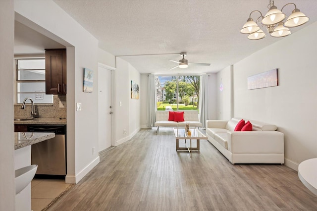1040 SE 4th Ave Unit 129, Deerfield Beach, FL 33441 - living room featuring light wood finished floors, a ceiling fan, a chandelier, and a textured ceiling