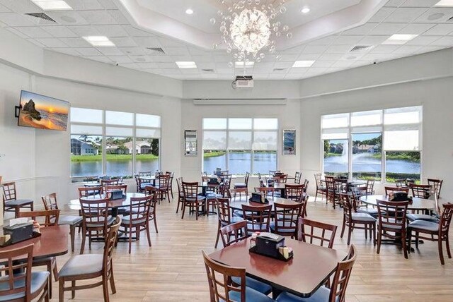 7585 Las Cruces Ct, Boynton Beach, FL 33437 - dining room with light wood finished floors, a paneled ceiling, a water view, a chandelier, and a high ceiling