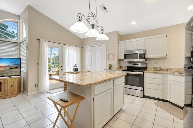 12697 Coral Breeze Dr, Wellington, FL 33414 - kitchen featuring stainless steel appliances, light tile patterned flooring, a center island, plenty of natural light, and lofted ceiling