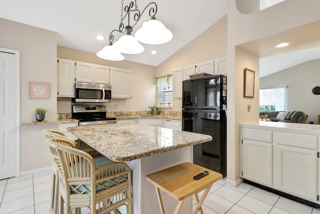 12697 Coral Breeze Dr, Wellington, FL 33414 - kitchen featuring stainless steel appliances, vaulted ceiling, light tile patterned floors, white cabinetry, and a kitchen bar
