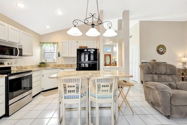 12697 Coral Breeze Dr, Wellington, FL 33414 - kitchen featuring appliances with stainless steel finishes, open floor plan, light tile patterned floors, light stone countertops, and lofted ceiling