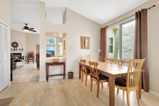 12697 Coral Breeze Dr, Wellington, FL 33414 - dining area featuring light wood-style floors, ceiling fan, baseboards, lofted ceiling, and a glass covered fireplace