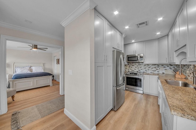 1140 Mahogany Way Unit 103, Delray Beach, FL 33445 - kitchen with appliances with stainless steel finishes, a sink, light wood-type flooring, light stone counters, and tasteful backsplash