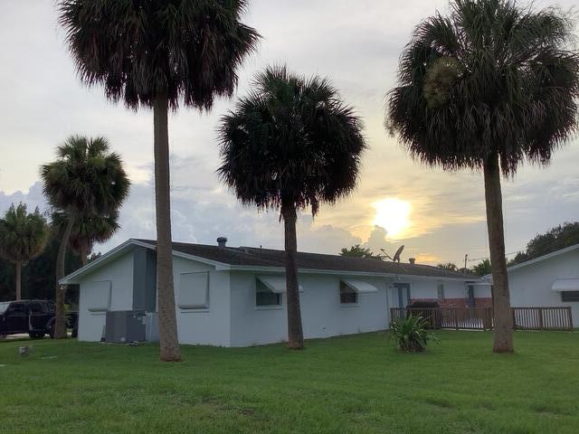 1210 Hartman Rd, Fort Pierce, FL 34947 - back of property at dusk with stucco siding and central AC