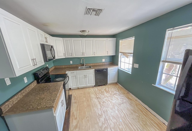 2818 Alabama St, West Palm Beach, FL 33406 - kitchen with black appliances, a sink, dark countertops, and white cabinetry
