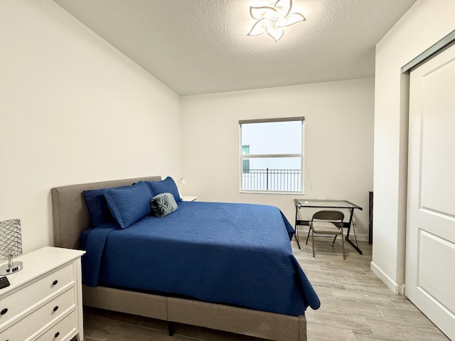 1130 Tangled Orchard Trce, The Acreage, FL 33470 - bedroom featuring a textured ceiling, light wood-style floors, and baseboards