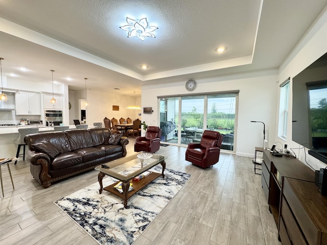 1130 Tangled Orchard Trce, The Acreage, FL 33470 - living room with a tray ceiling, light wood-style floors, a textured ceiling, recessed lighting, and baseboards