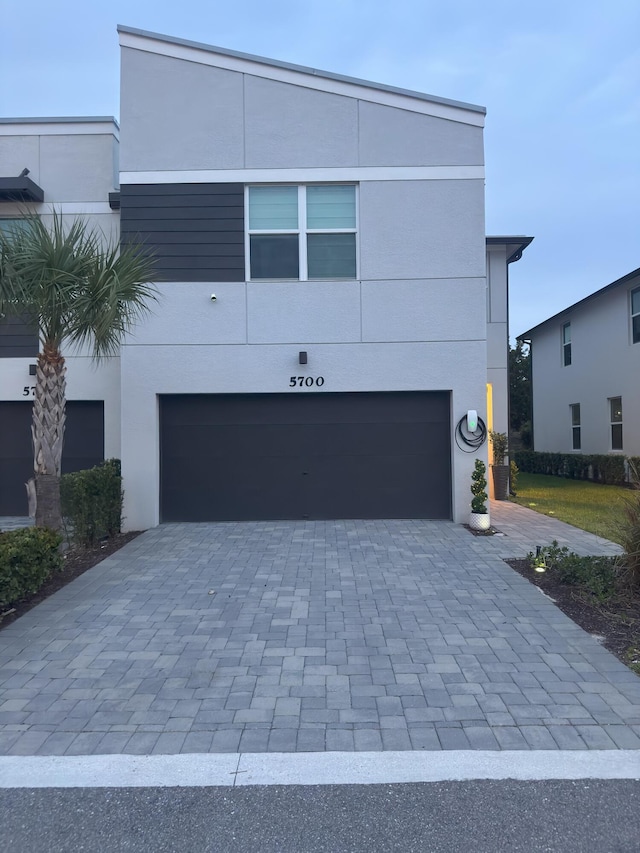 5700 Mentmore Dr, Mangonia Park, FL 33407 - view of front of house featuring a garage, decorative driveway, and stucco siding
