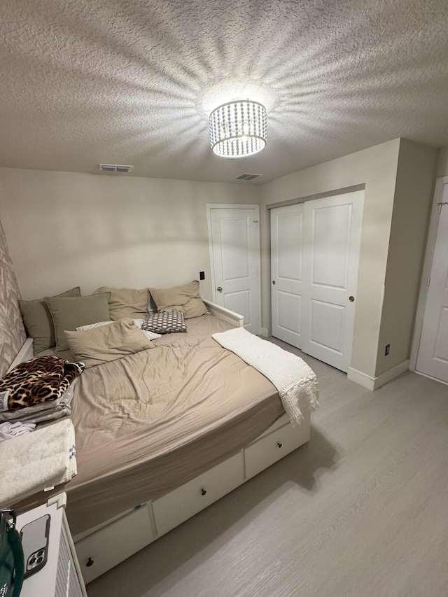 5700 Mentmore Dr, Mangonia Park, FL 33407 - bedroom with light wood-style flooring, a textured ceiling, a closet, and baseboards