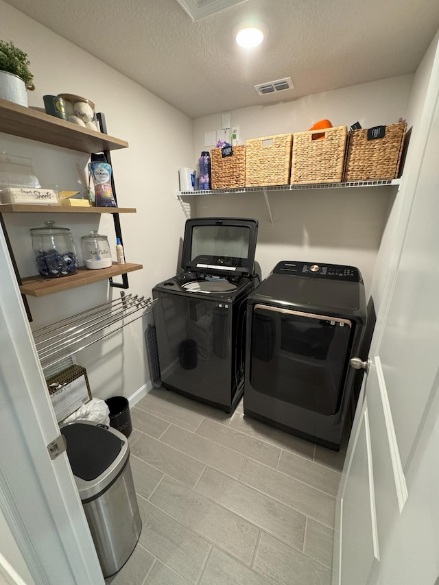 5700 Mentmore Dr, Mangonia Park, FL 33407 - laundry room featuring washing machine and dryer, a textured ceiling, light tile patterned floors, and baseboards
