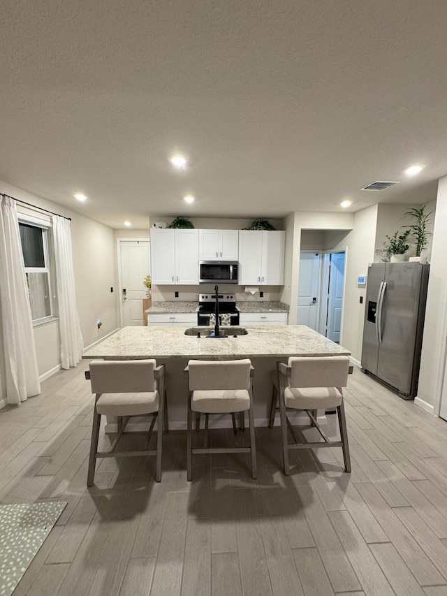 5700 Mentmore Dr, Mangonia Park, FL 33407 - kitchen with stainless steel appliances, light wood-type flooring, a sink, a kitchen bar, and recessed lighting