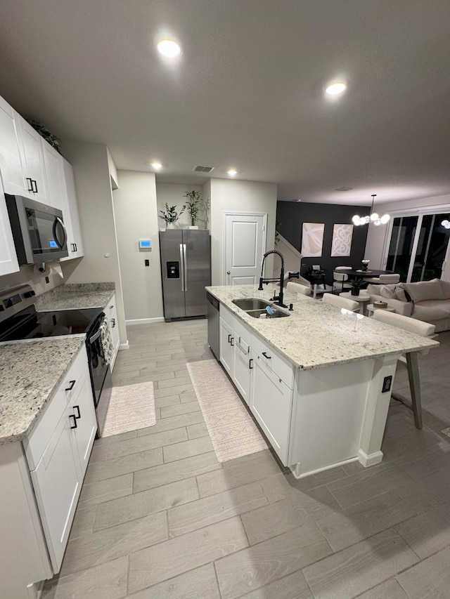 5700 Mentmore Dr, Mangonia Park, FL 33407 - kitchen with appliances with stainless steel finishes, a sink, a center island with sink, white cabinets, and recessed lighting