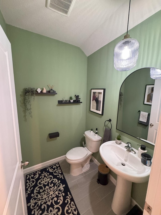 5700 Mentmore Dr, Mangonia Park, FL 33407 - bathroom featuring baseboards, tile patterned flooring, toilet, lofted ceiling, and a textured ceiling