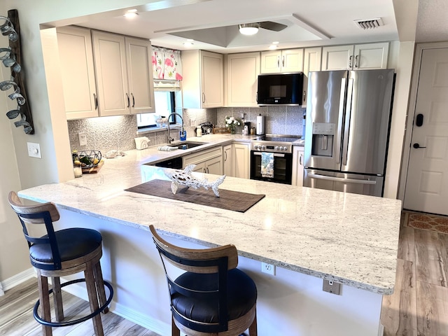 301 SW S River Dr Unit 206, Stuart, FL 34997 - kitchen featuring appliances with stainless steel finishes, a sink, a peninsula, and light stone countertops
