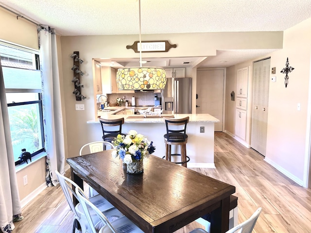 301 SW S River Dr Unit 206, Stuart, FL 34997 - dining area featuring light wood finished floors, a textured ceiling, and baseboards