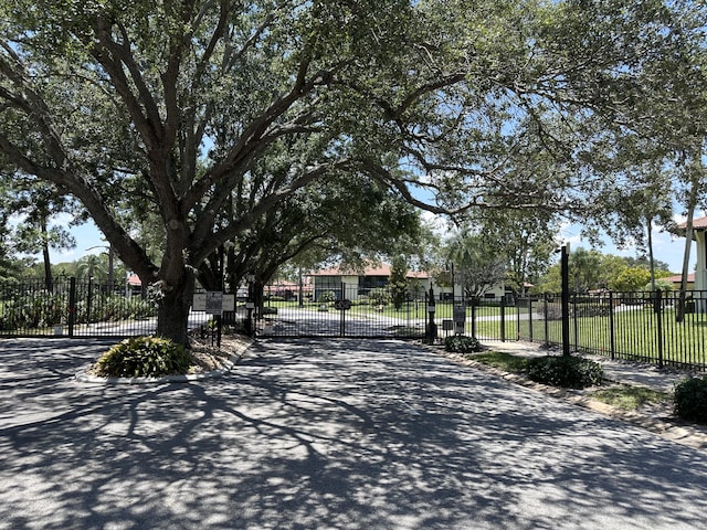 301 SW S River Dr Unit 206, Stuart, FL 34997 - view of asphalt road featuring curbs, a gate, and a gated entry