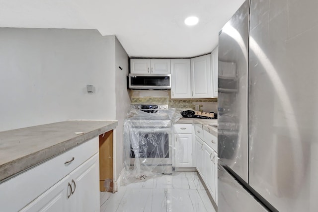 1112 S K St, Lake Worth Beach, FL 33460 - kitchen with appliances with stainless steel finishes, light marble finish floors, white cabinetry, tasteful backsplash, and light countertops