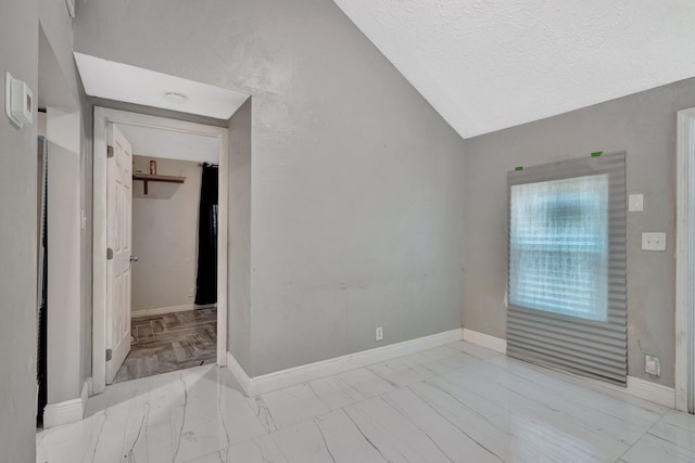 1112 S K St, Lake Worth Beach, FL 33460 - empty room featuring marble finish floors, vaulted ceiling, baseboards, and a textured ceiling