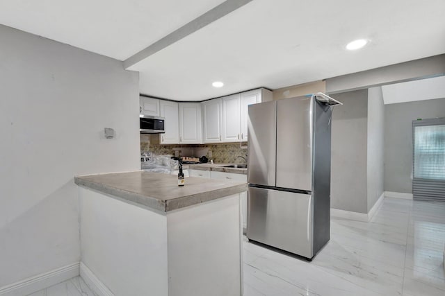 1112 S K St, Lake Worth Beach, FL 33460 - kitchen featuring stainless steel appliances, white cabinets, light marble finish flooring, tasteful backsplash, and baseboards