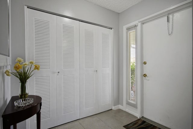 1233 S Lakes End Dr Unit A, Fort Pierce, FL 34982 - entryway featuring light tile patterned flooring, a textured ceiling, and baseboards