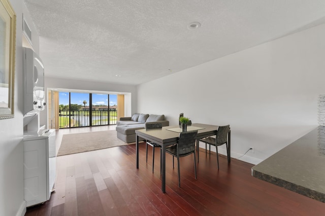 4489 Luxemburg Ct Unit 306, Lake Worth, FL 33467 - dining area featuring stacked washing machine and dryer, dark wood-style flooring, baseboards, and a textured ceiling
