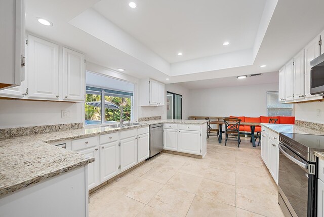 2590 Monaco Ter, Palm Beach Gardens, FL 33410 - kitchen featuring a sink, appliances with stainless steel finishes, a tray ceiling, recessed lighting, and a peninsula