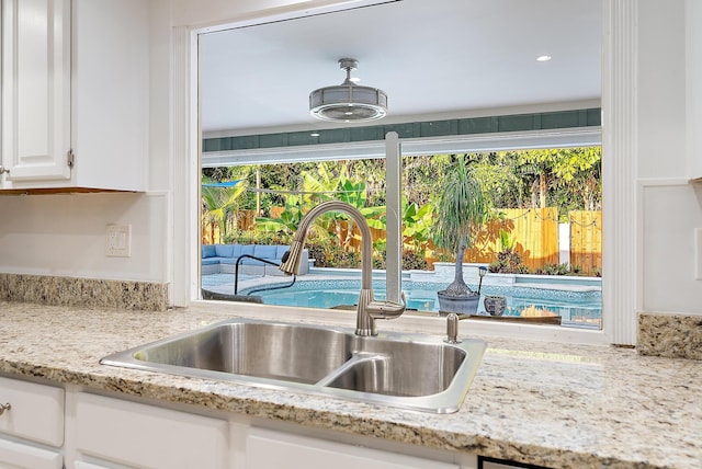 2590 Monaco Ter, Palm Beach Gardens, FL 33410 - kitchen view of a sink, white cabinets, and light stone countertops