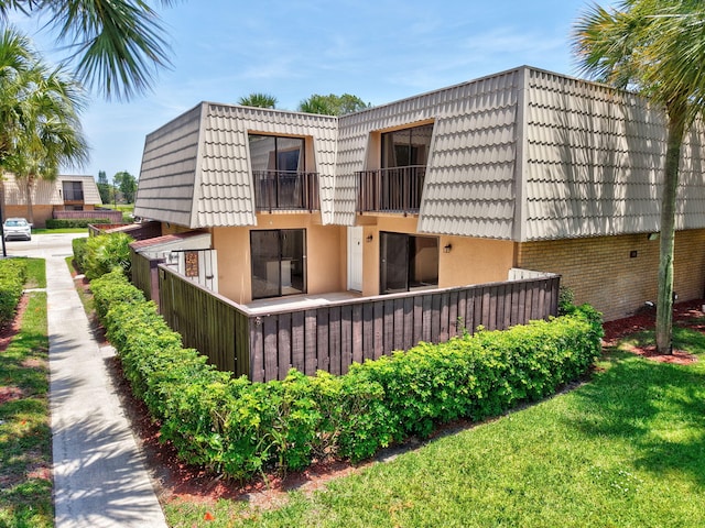 6604 66th Way, West Palm Beach, FL 33409 - back of house with mansard roof, a balcony, stucco siding, and brick siding