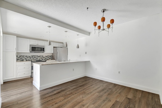 6604 66th Way, West Palm Beach, FL 33409 - kitchen with appliances with stainless steel finishes, a chandelier, a peninsula, backsplash, and white cabinetry
