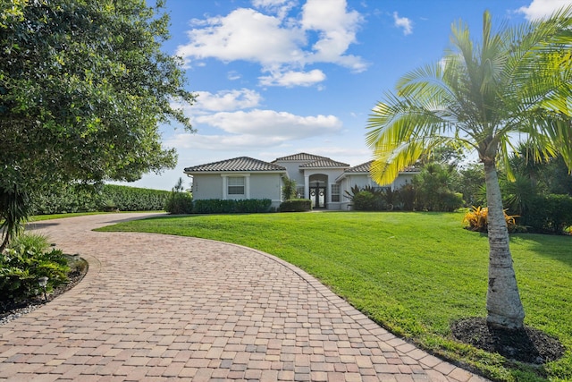 1936 SW Wood Duck Ln, Palm City, FL 34990 - mediterranean / spanish house featuring curved driveway, a front lawn, and stucco siding