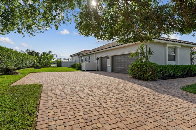 1936 SW Wood Duck Ln, Palm City, FL 34990 - view of home's exterior featuring a garage, decorative driveway, stucco siding, and a tile roof