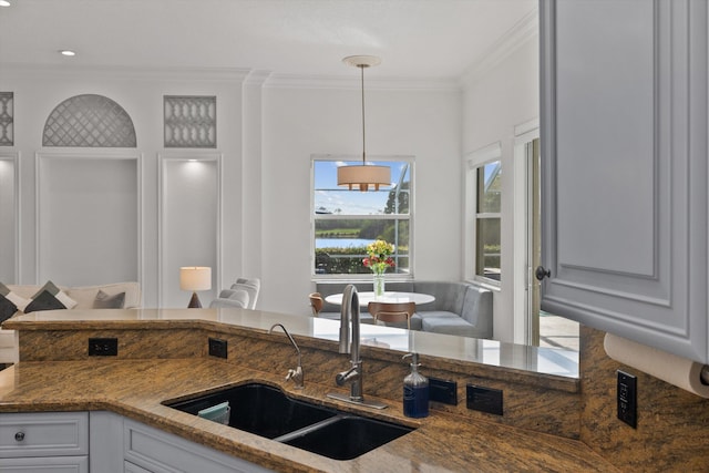 1936 SW Wood Duck Ln, Palm City, FL 34990 - kitchen with crown molding, a sink, dark stone counters, hanging light fixtures, and white cabinetry