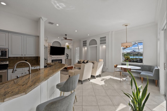 1936 SW Wood Duck Ln, Palm City, FL 34990 - kitchen featuring a stone fireplace, dark stone countertops, a ceiling fan, backsplash, and appliances with stainless steel finishes