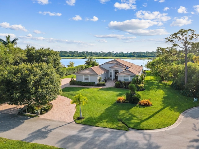 1936 SW Wood Duck Ln, Palm City, FL 34990 - view of front of home with a water view, a front yard, stucco siding, decorative driveway, and a tiled roof
