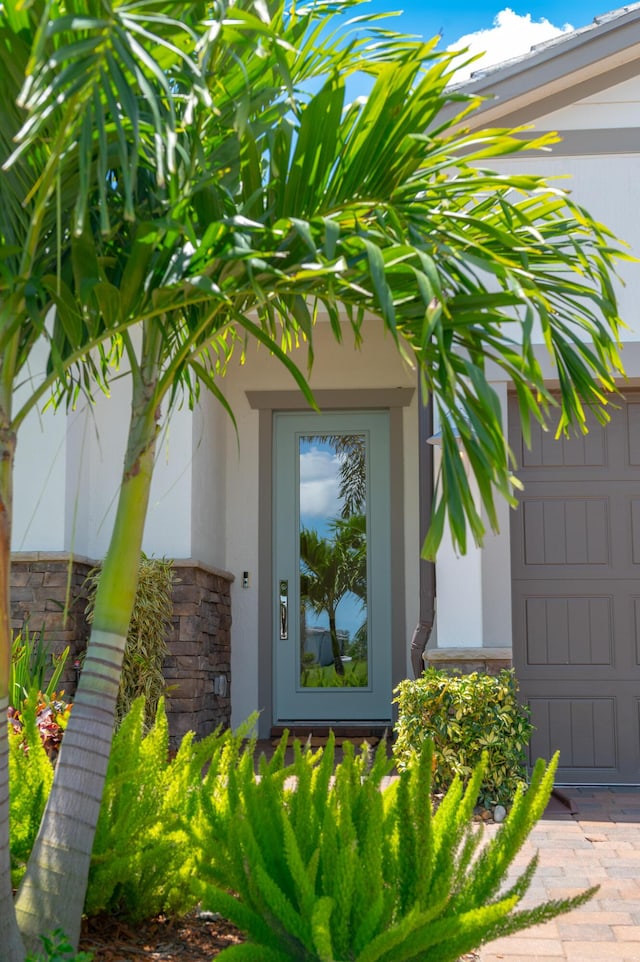 640 SE Boboli Way, Port Saint Lucie, FL 34984 - property entrance featuring stone siding, a garage, and stucco siding