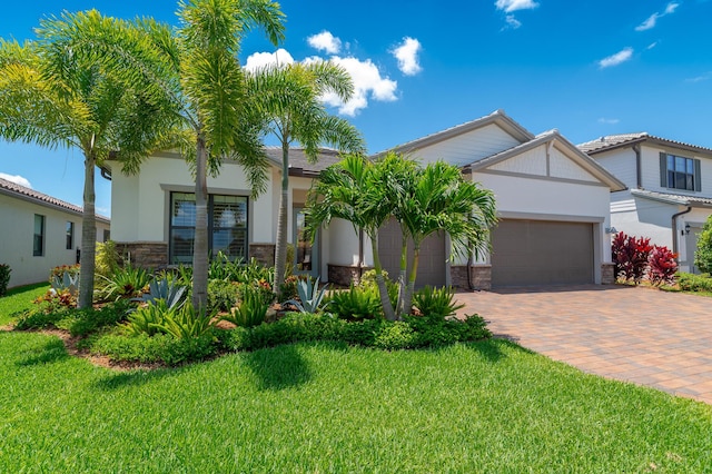 640 SE Boboli Way, Port Saint Lucie, FL 34984 - view of front facade featuring stone siding, decorative driveway, a front yard, and an attached garage