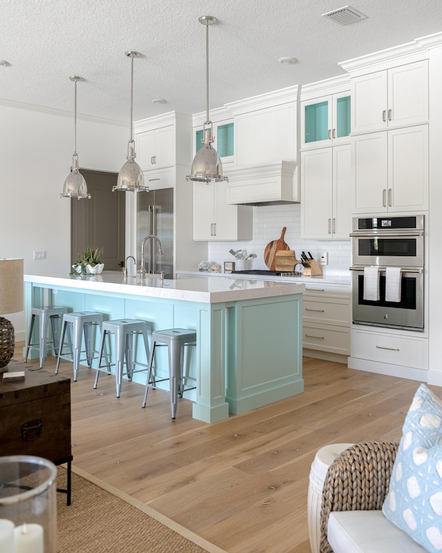 640 SE Boboli Way, Port Saint Lucie, FL 34984 - kitchen with appliances with stainless steel finishes, a breakfast bar, light countertops, white cabinetry, and light wood-style floors
