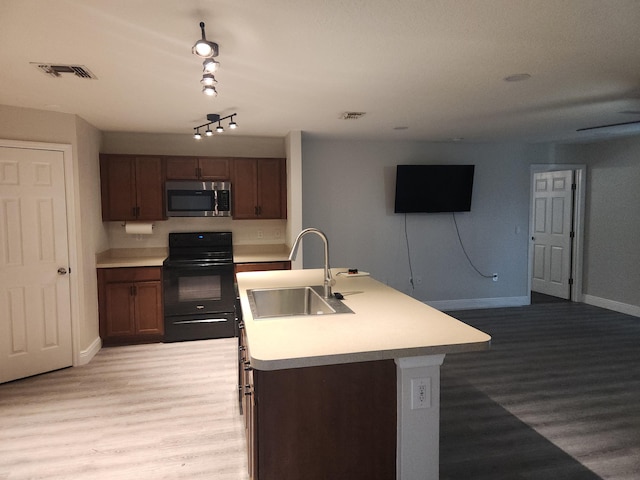 1721 SE Biddle Ln, Port Saint Lucie, FL 34983 - kitchen featuring black range with electric cooktop, stainless steel microwave, a sink, and light wood-style floors